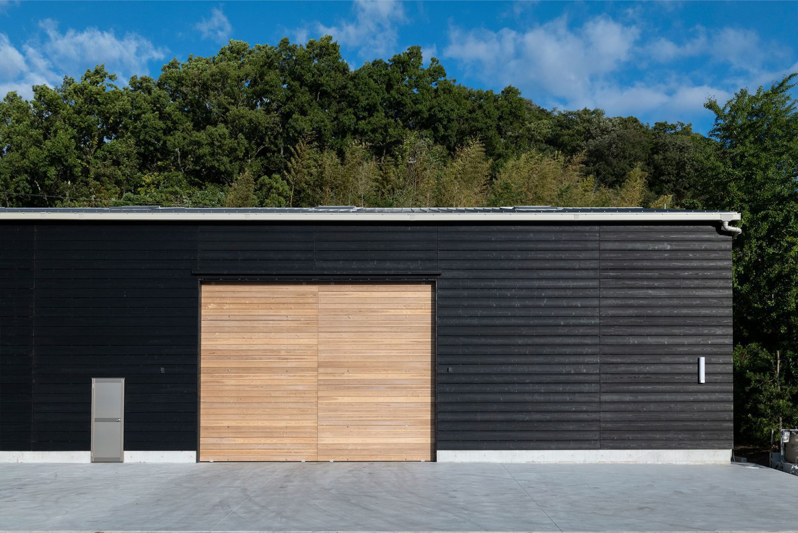Industrial building facade with Yakisugi a.k.a Shousugiban cedar cladding and large timber door.